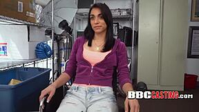 A young Latin woman chokes on a large black penis, covered in saliva.