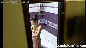 A tattooed brunette indulges in a bath time shower, showcasing her naked beauty