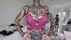 Melody Radford, a gorgeous Goth milf, shows off her big tits and big ass in black and purple lingerie and a micro bikini in a steamy solo video.