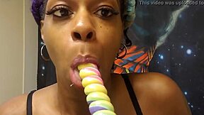 A black beauty enjoys sucking a lollipop shaped like a unicorn