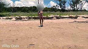 Naked wife plays football at a clothed beach where people tend to sunbathe