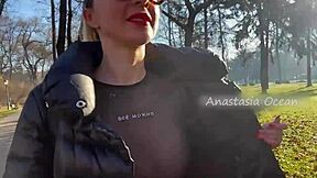 Beautiful woman exposes her large breasts while she is on a walk in the park