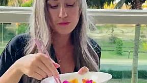 Beautiful girl model picks up chopsticks and exotic fruits in her dress